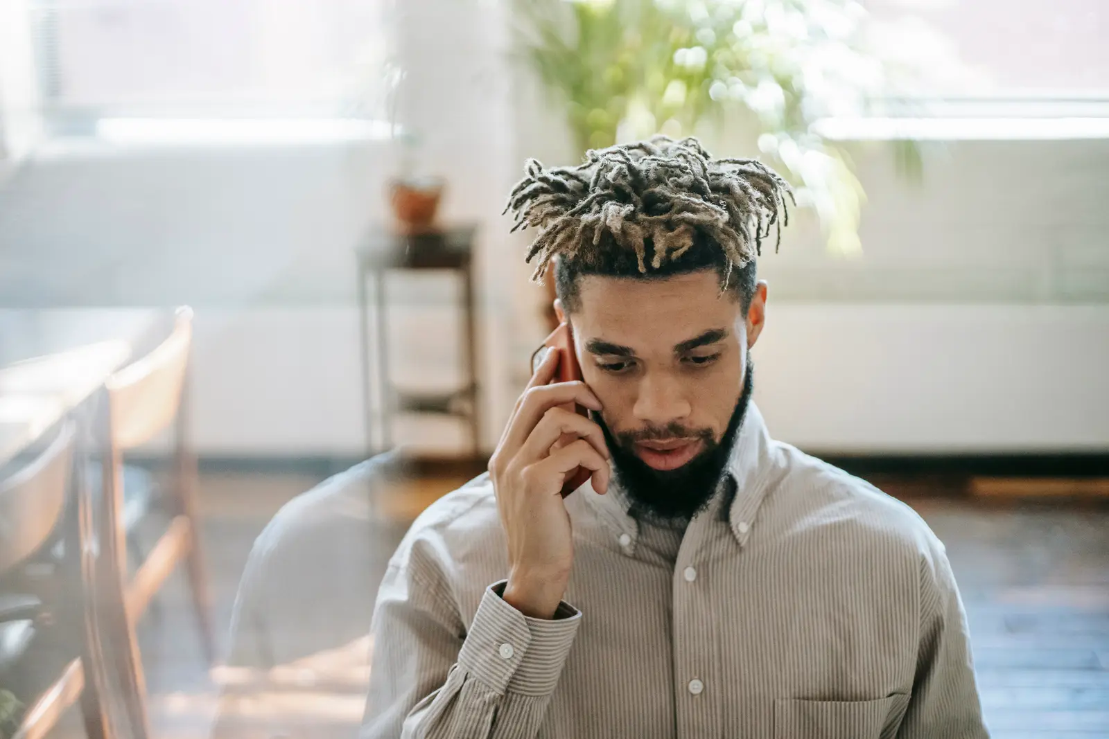A man in a sunlit office speaking on a phone.
