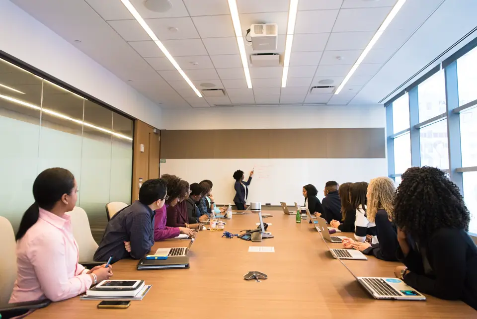 A diverse team around a boardroom table with laptops.